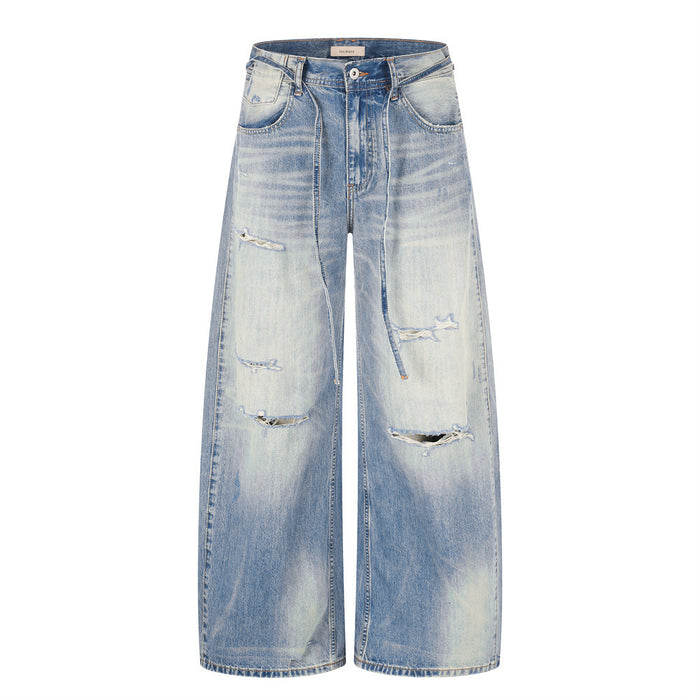 Men's wide-leg distressed jeans in gradient washed blue denim with ripped details and contrast back pocket patch