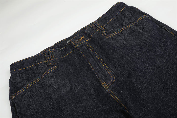 Top view of dark indigo jeans showing waistband, fly, and embossed pocket detail