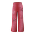 Front view of pink acid-wash wide-leg sweatpants with scattered graffiti-style text and drawings