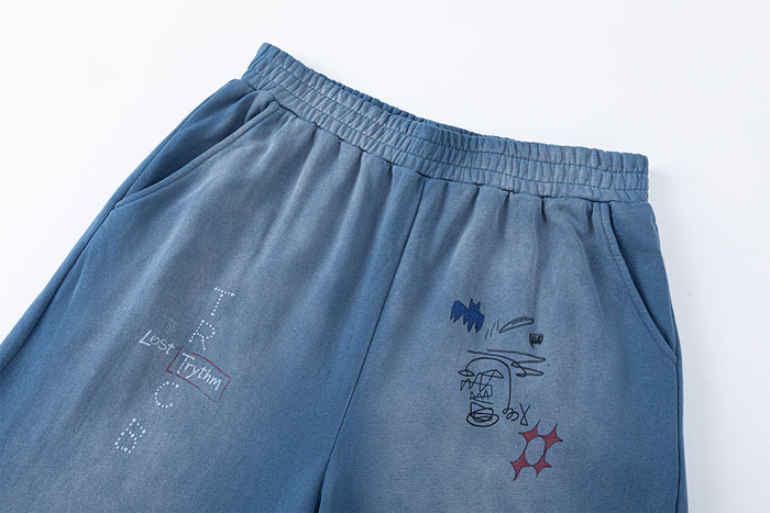 Close-up of blue sweatpants waistband, side pocket, and colorful graffiti-style graphics