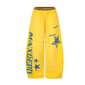 Wide-leg graphic sweatpants in yellow with blue star and letter prints, elastic drawstring waist and ankle zip detail