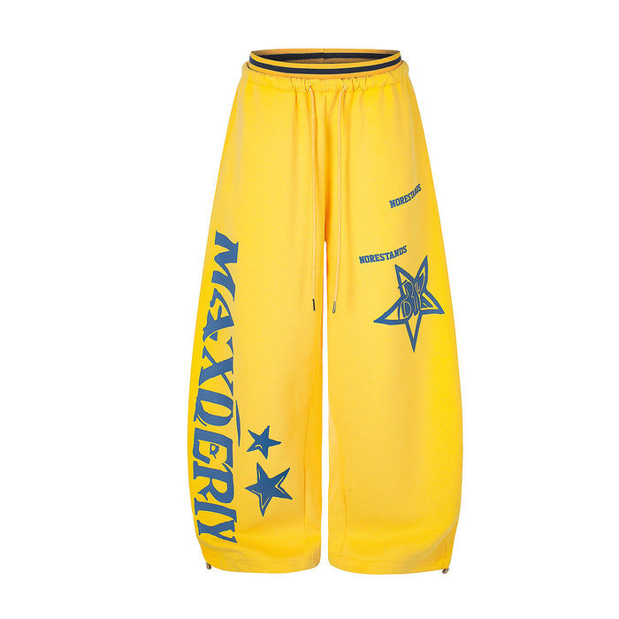 Wide-leg graphic sweatpants in yellow with blue star and letter prints, elastic drawstring waist and ankle zip detail