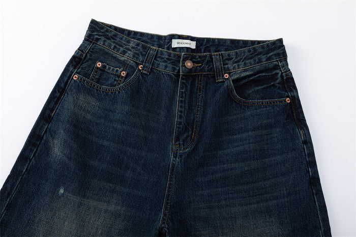 Front waist of dark blue jeans with button closure, belt loops, and copper rivets