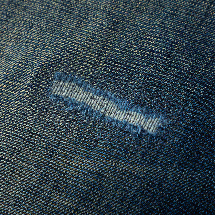 Close-up of distressed denim with small ripped tear and frayed edges