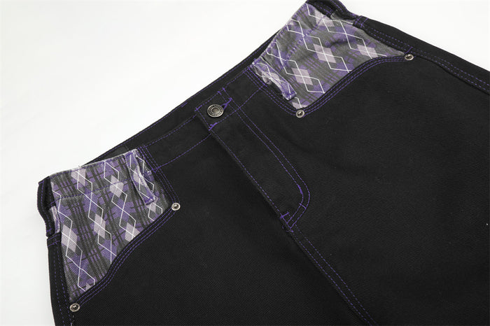 Close-up of black jeans waist with purple argyle patchwork panels and button closure