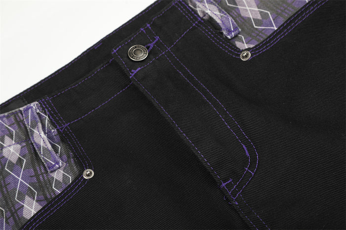 Close-up of black jeans waistband showing purple topstitching and argyle patchwork panel