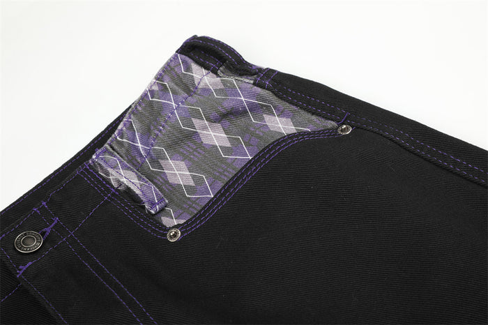Waist detail of black jeans with purple argyle patchwork and metal button closure