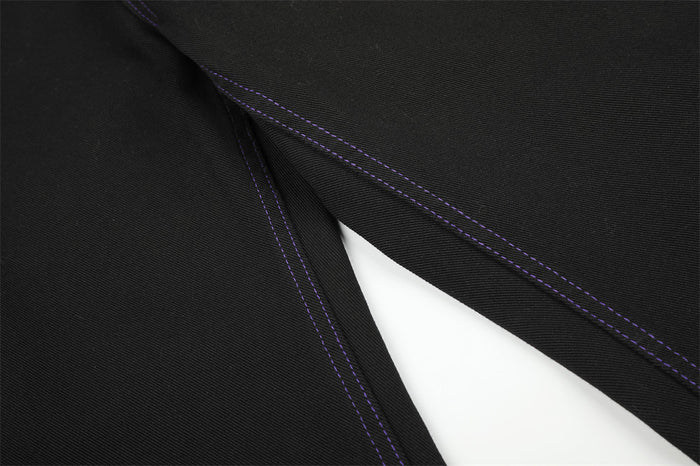 Close-up of black denim leg seam with purple topstitching on wide-leg jeans