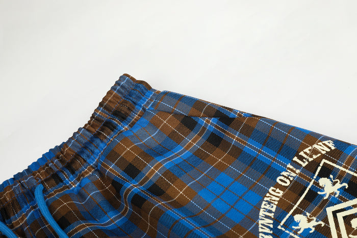 Detailed view of the elastic blue and brown plaid waistband, blue drawstring, and partial white graphic