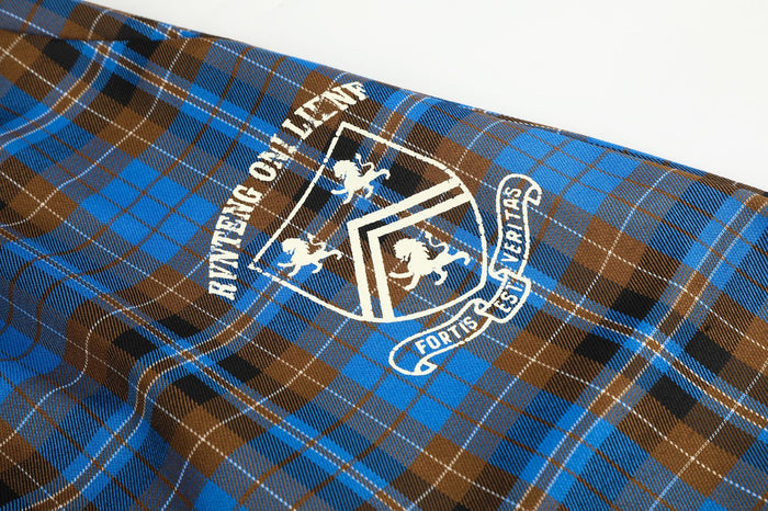 Close-up of a white shield crest graphic printed on blue and brown tartan fabric