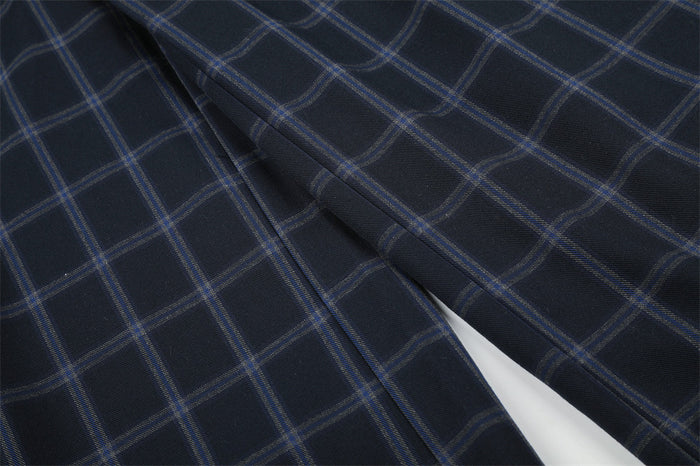 Close-up of the trouser leg seam on navy plaid fabric
