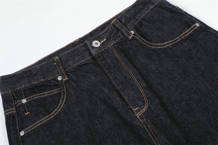 Close-up of front waistband and pocket on dark raw denim jeans with tan topstitching