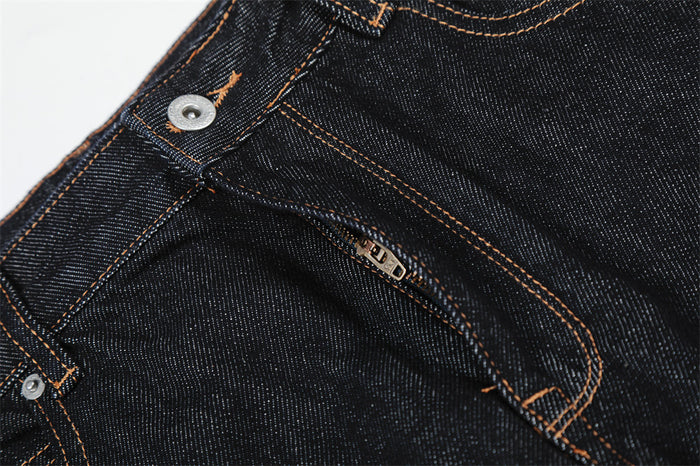 Close-up of front fly zipper and pocket seam on dark raw denim jeans