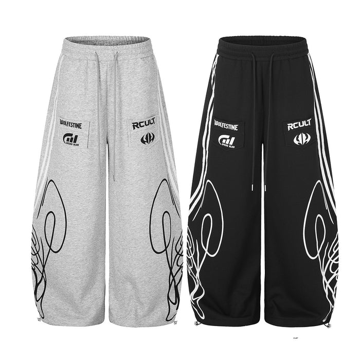 Front view of wide-leg sweatpants in heather gray and black with white side stripes and bold leg graphics