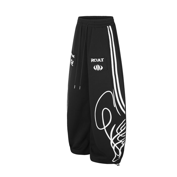 Angled front view of black wide-leg sweatpants with triple white side stripes, drawstring waist and graphic leg print