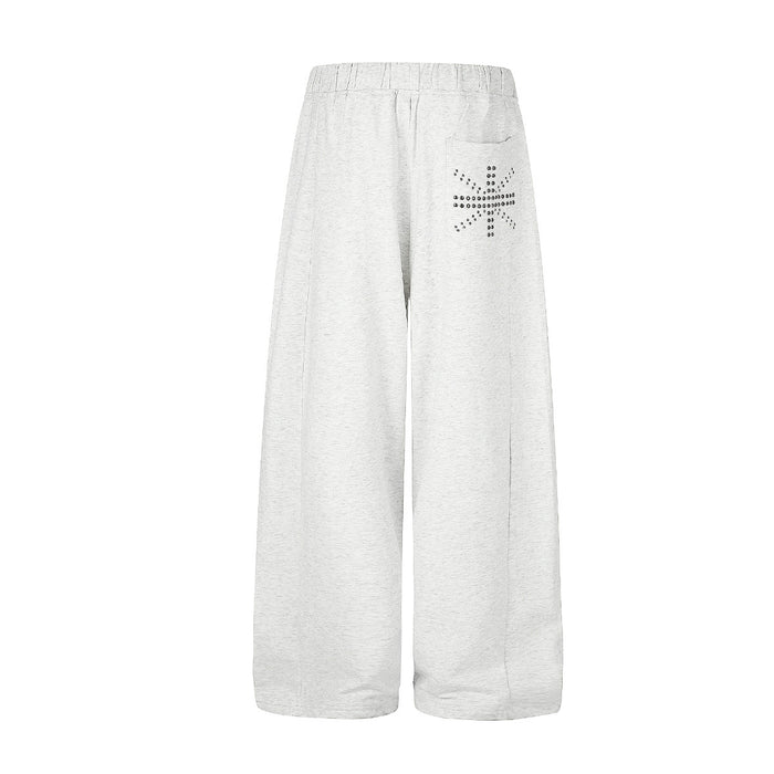 Front view of light gray wide-leg sweatpants with a studded cross detail near the upper pocket