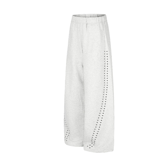 Angled view of light gray wide-leg sweatpants showing the curved studded side-panel design