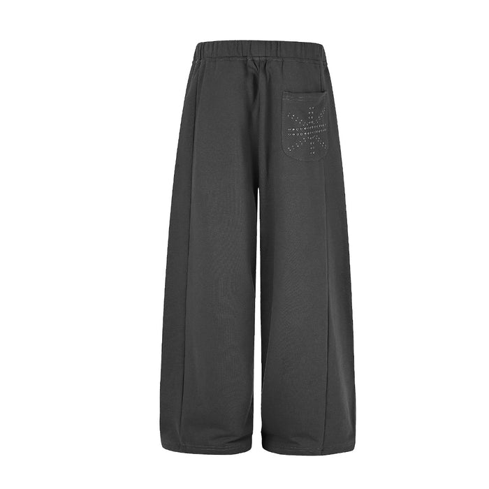 Back view of black wide-leg sweatpants with a studded cross detail on the upper pocket