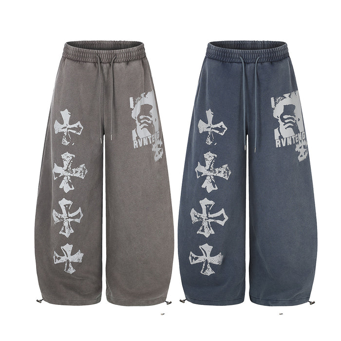 Front view of wide-leg acid-wash sweatpants in gray and blue with white cross prints and graphic panels