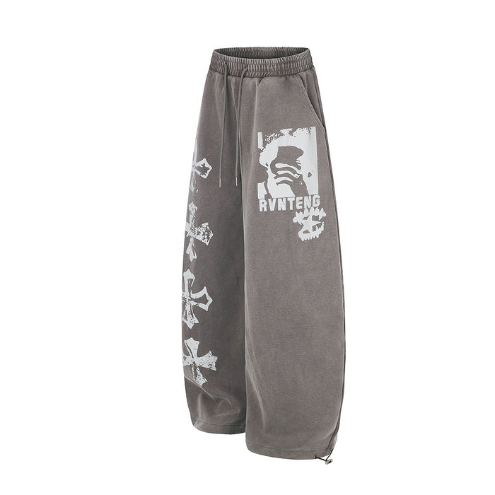 Angled view of gray wide-leg sweatpants showing the white graphic panel and cross prints along one side
