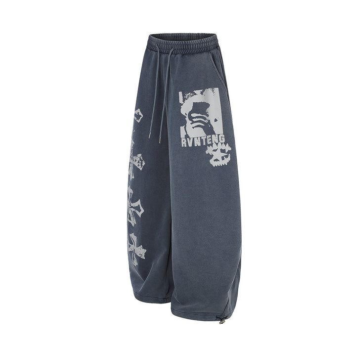 Angled view of blue wide-leg sweatpants showing the white graphic panel, side cross prints, and drawstring waist