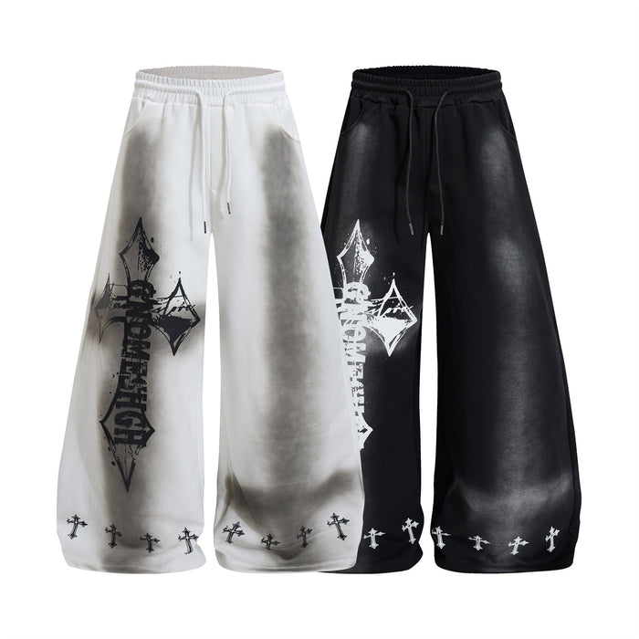 Wide-leg sweatpants in white and black with washed shading, gothic cross graphics, and repeated cross hems