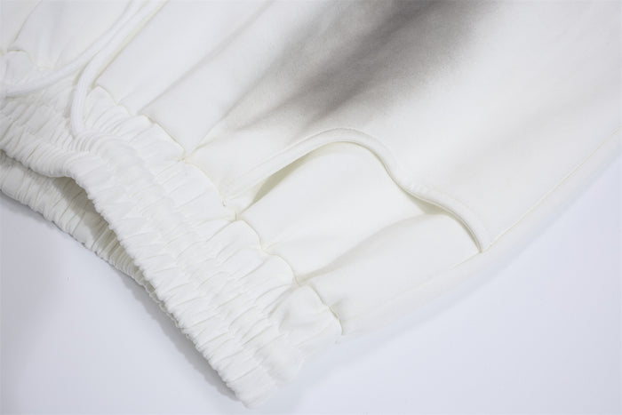 Close-up of white sweatpants waistband, drawcord, side pocket opening, and gathered elastic detailing