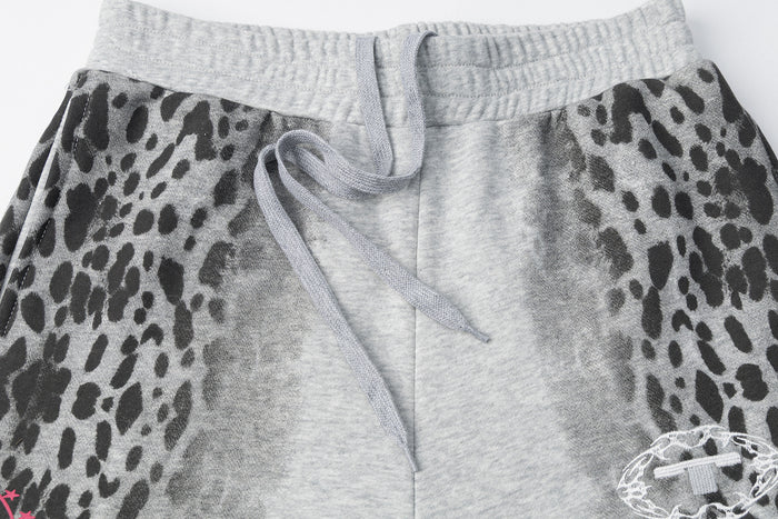 Close-up of gray elastic waistband, drawstring, leopard-print side panels, and partial embroidered badge