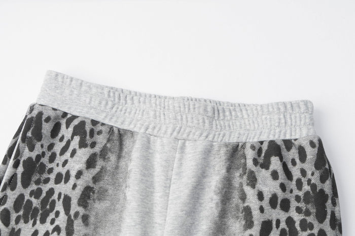 Close-up of the ribbed gray elastic waistband above the leopard-print panels on the sweatpants