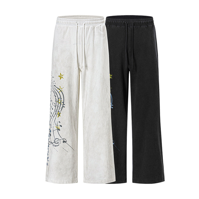 Front view of wide-leg sweatpants in cream and black with colorful music note and star graphics