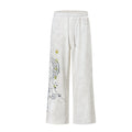 Wide-leg washed sweatpants with music note and star graphic print on left leg, shown in off-white and black