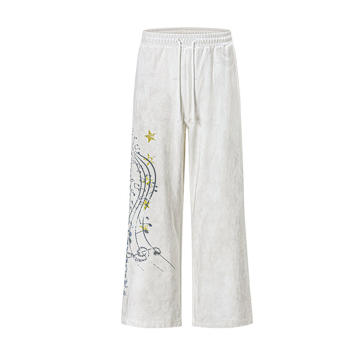 Wide-leg washed sweatpants with music note and star graphic print on left leg, shown in off-white and black