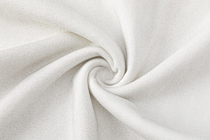 Close-up of soft-looking cream textured knit fabric gathered into a spiral fold