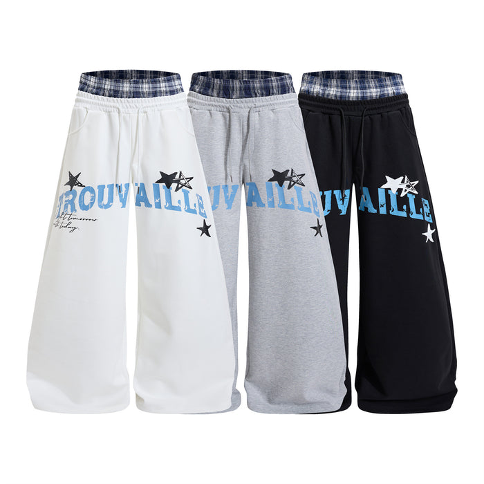Four wide-leg sweatpants in white, gray, and black with blue graphic lettering, star prints, and plaid waistbands
