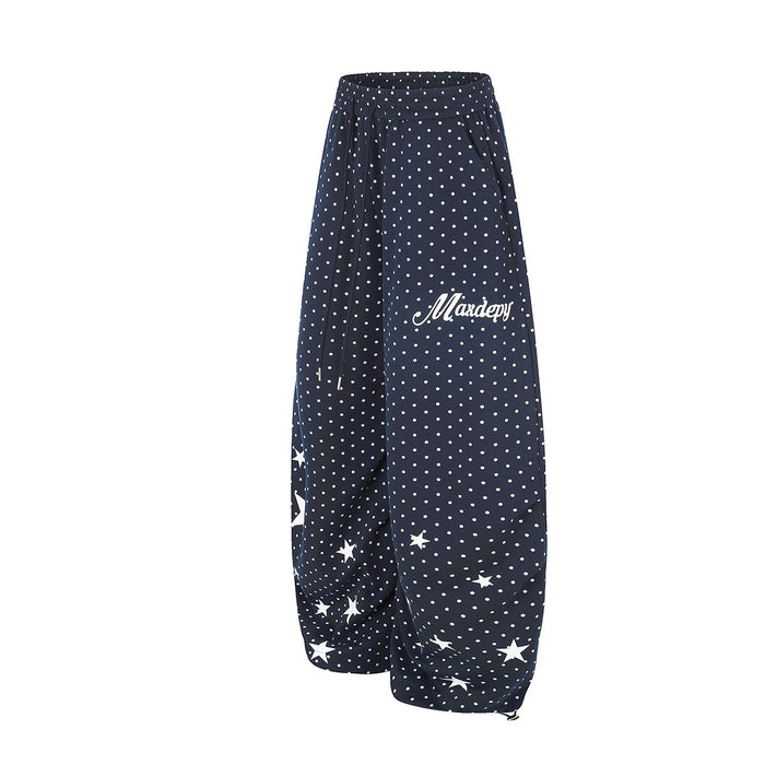 Side view of navy wide-leg sweatpants with white polka dots, star accents, and white script text