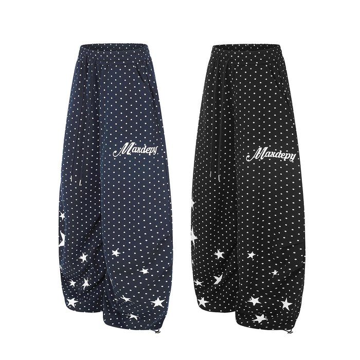 Side views of navy and black wide-leg sweatpants with white polka dots, star prints, and script text