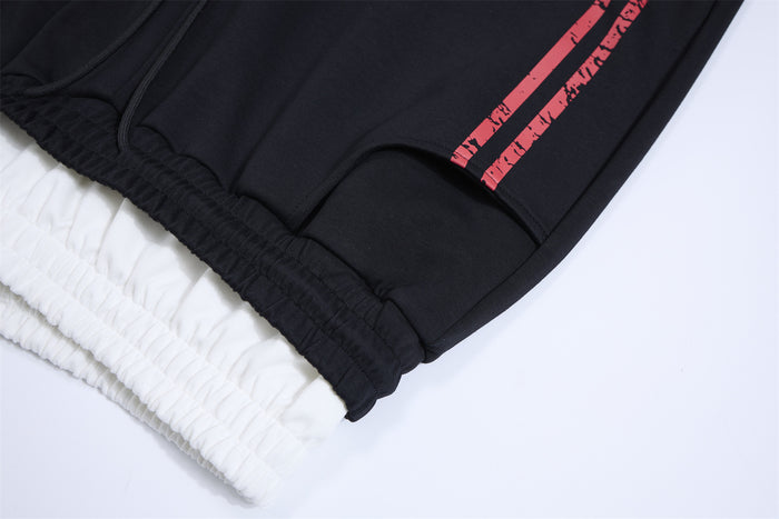 Close-up of black sweatpants layered waistband and elastic edge with red printed side stripes