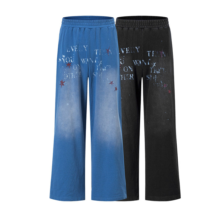 Front view of wide-leg blue and black pants with elastic waist, faded finish, star and letter graphics
