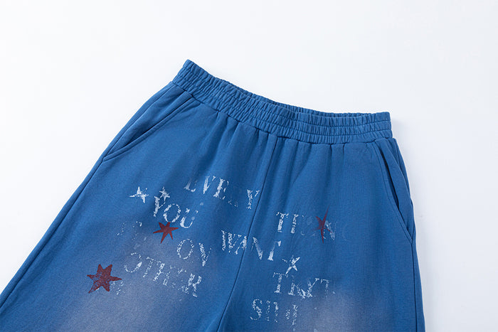 Close-up of blue pants showing the elastic waistband, side pockets, faded finish and star letter graphics