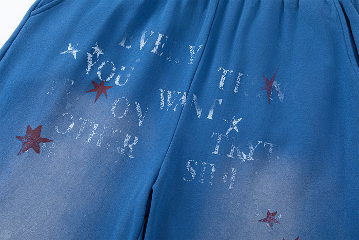 Detailed view of distressed white lettering and red star graphics on blue pants