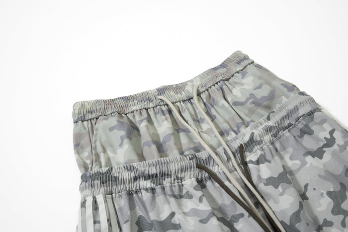 Close-up of elastic waistband and drawstrings on gray camouflage mesh track pants