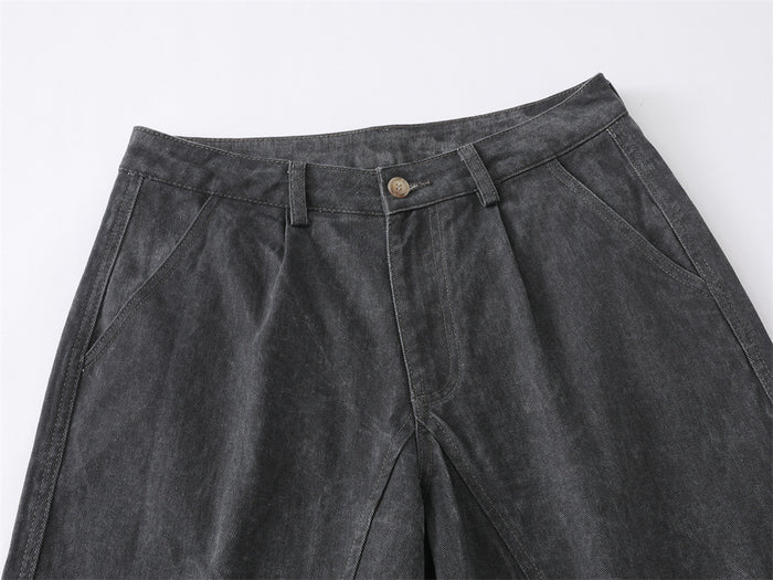 Close-up of front waistband on gray denim jeans with button, belt loops, and pleats