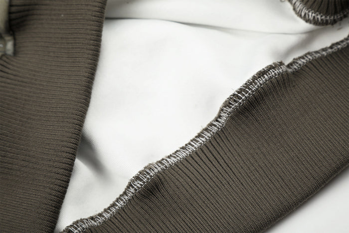 Close-up of dark ribbed hoodie trim and visible overlock stitching along the garment seam