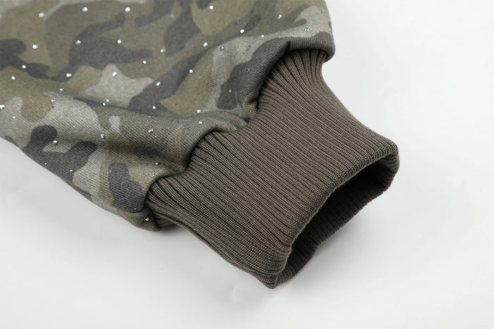 Close-up of a dark ribbed sleeve cuff attached to glitter-speckled gray-green camouflage fabric