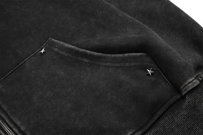 Close-up of a front kangaroo pocket with small star-shaped rivet details on washed charcoal fabric
